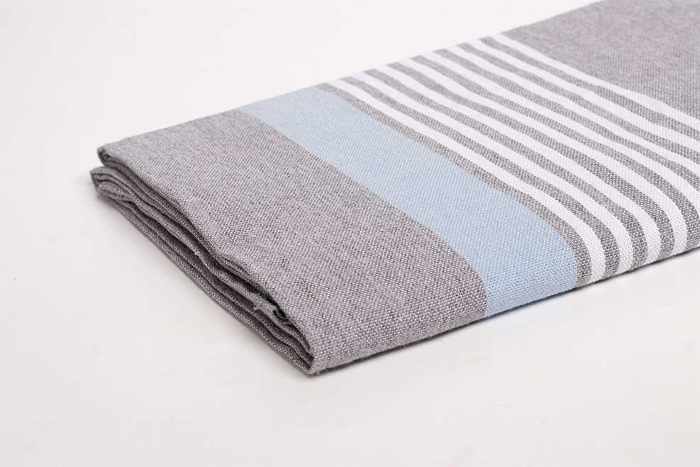 serviettes fouta pratiques pour le voyage : foutas grise à rayures pliée sur une table.