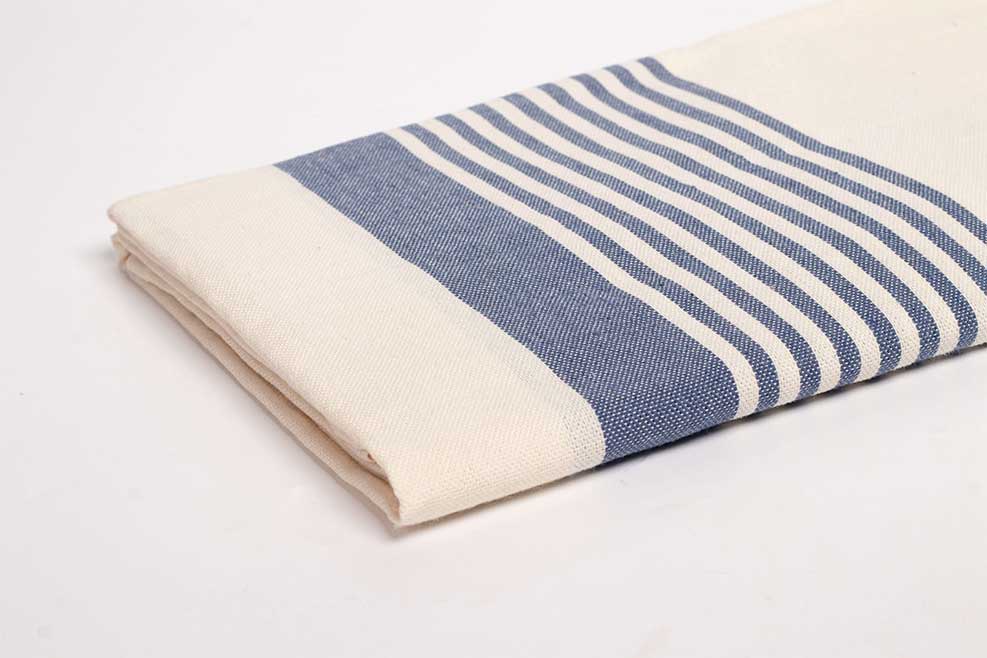 Serviette fouta pratiques pour le voyage à rayures bleues et blanches pliée.