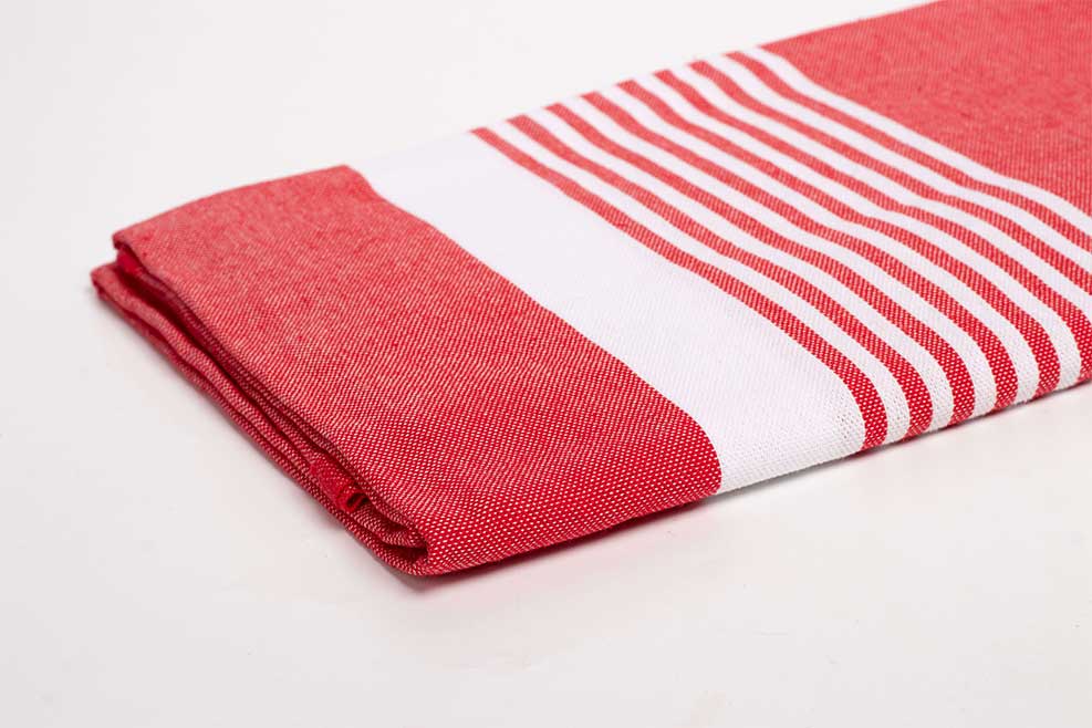 serviettes fouta pratiques pour le voyage : Torchon rouge et blanc plié sur surface.