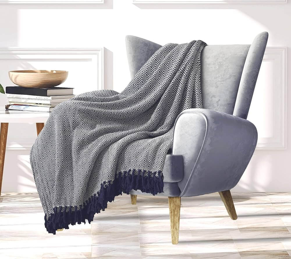 Fauteuil gris avec plaid géométrique noir et blanc.