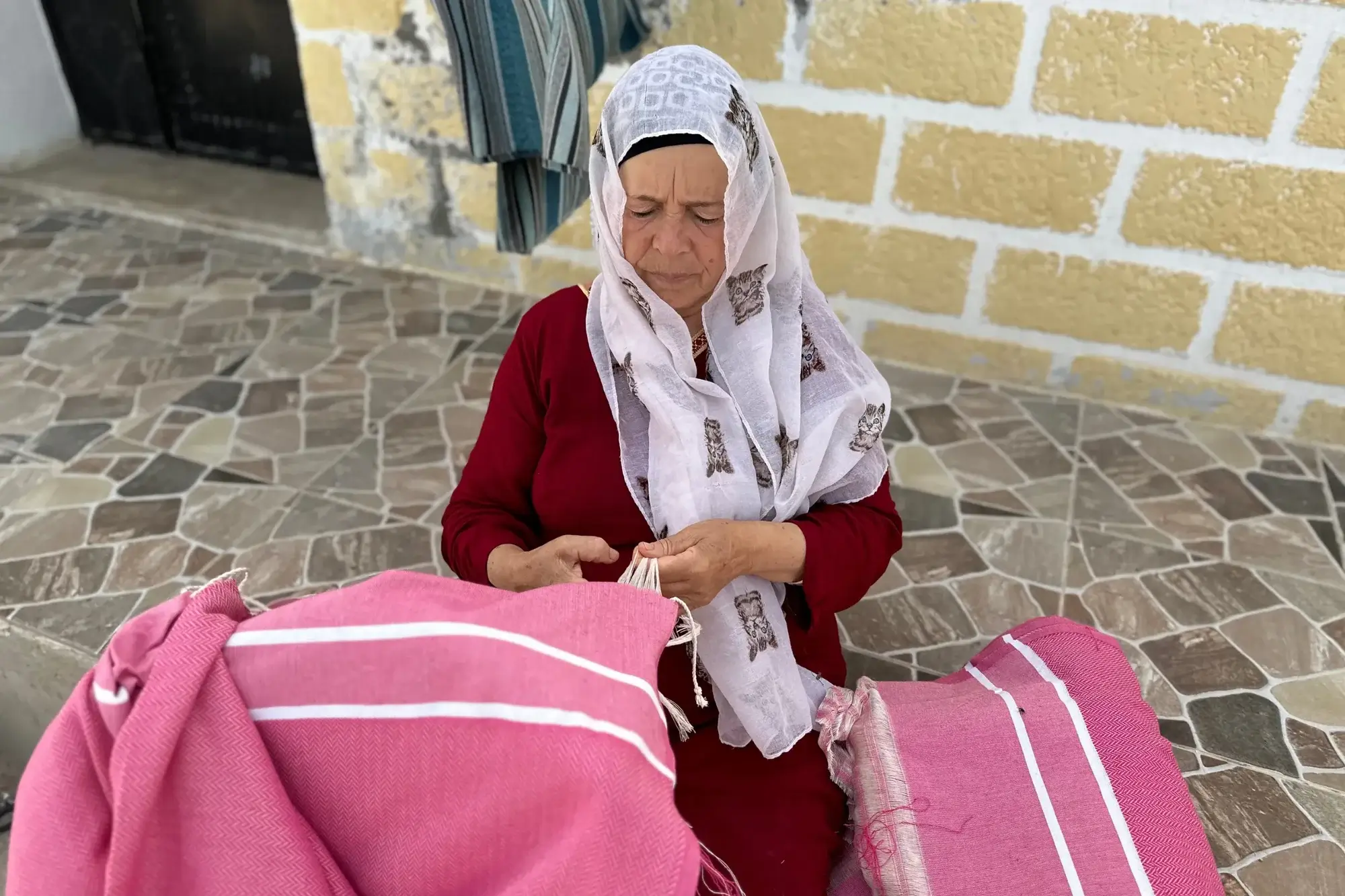 fouta artisanale france Femme tissant du tissu rose traditionnel.